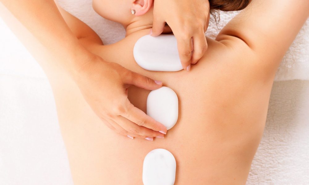 Young woman having hot stone massage in spa salon. Beauty treatment concept.
