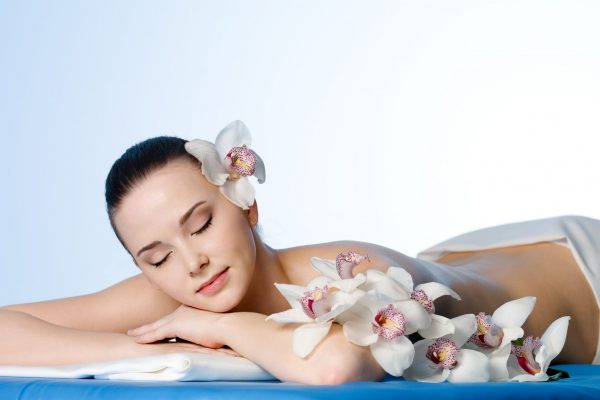 Woman resting in beauty spa salon  with flowers - colored background